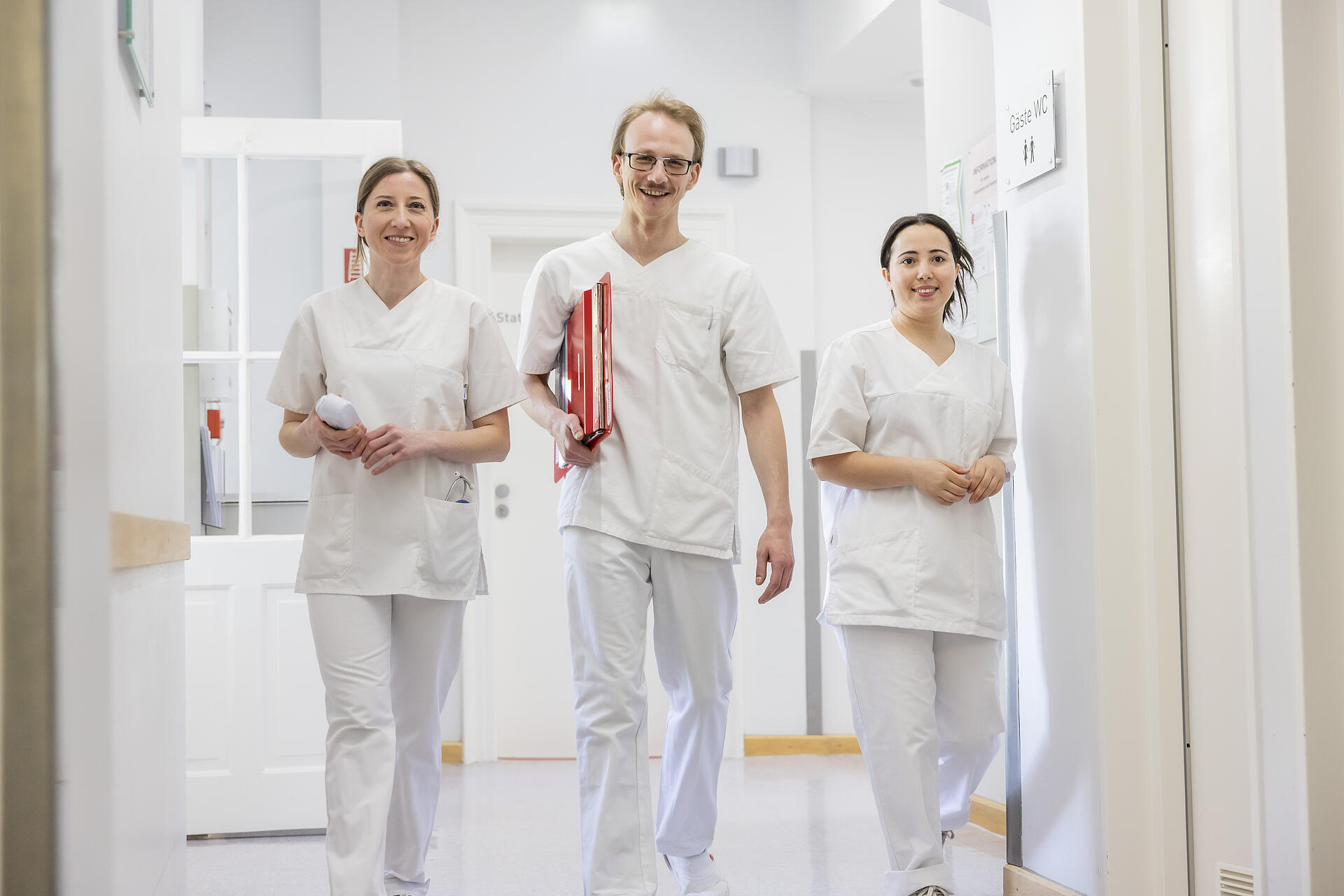 Drei Pflegekräfte in der Artemed Fachklinik München laufend auf dem Gang